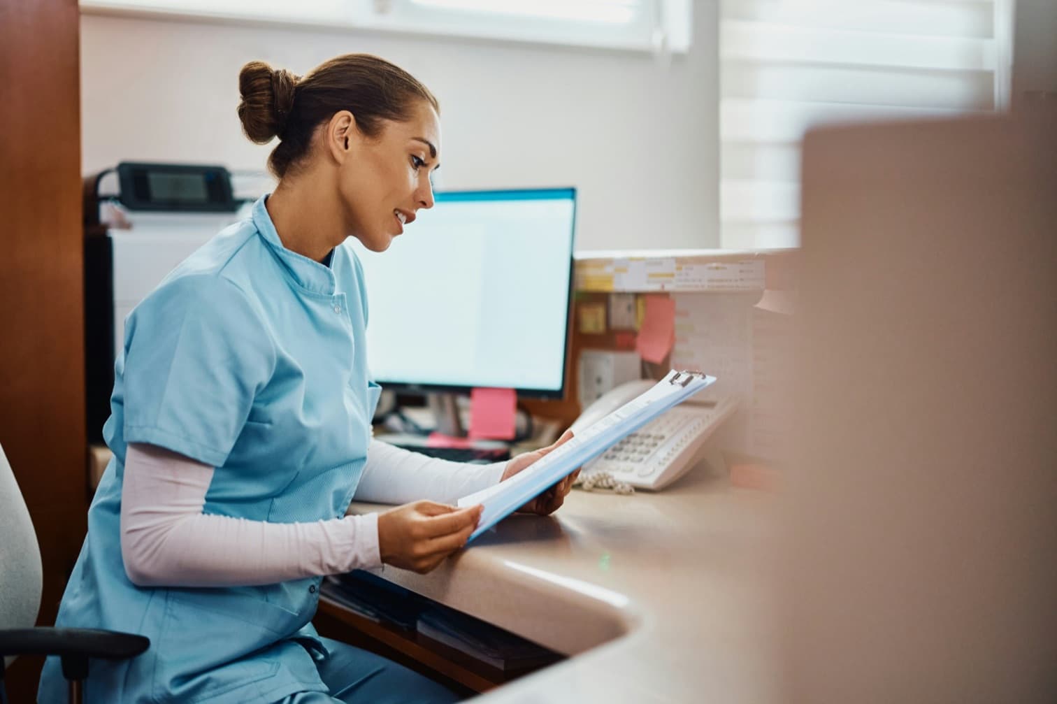 Une infirmière en santé au travail relit un dossier à l'accueil d'un centre médical